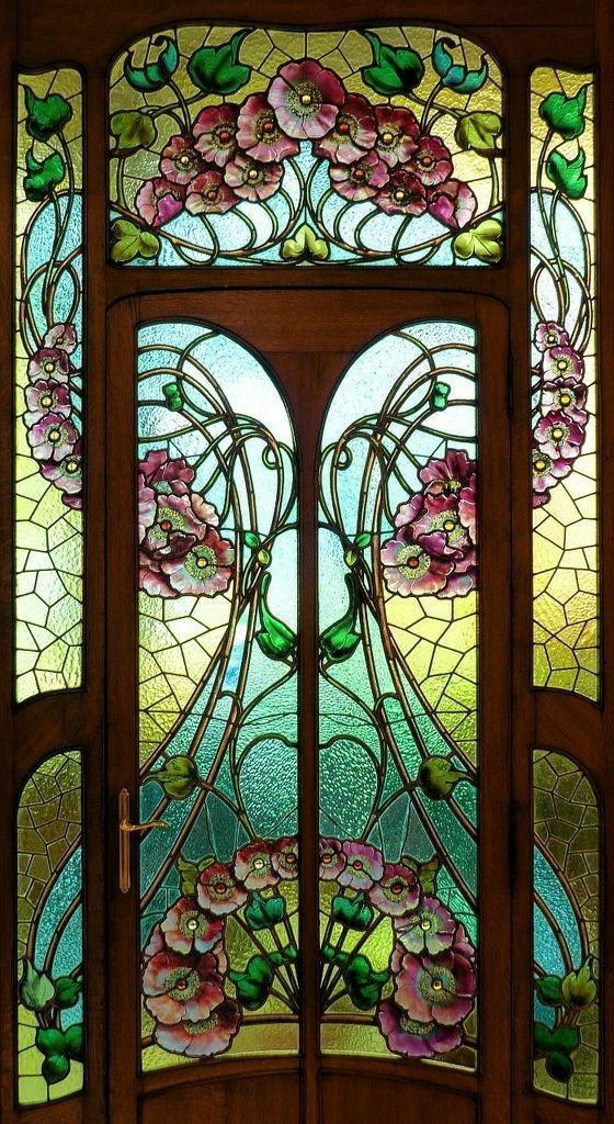 Vridial de una puerta, la puerta es de madera contonenado el vidrio mientras se forman figuras, en el vidrio estan dibujadas flores representativas del art nouveau