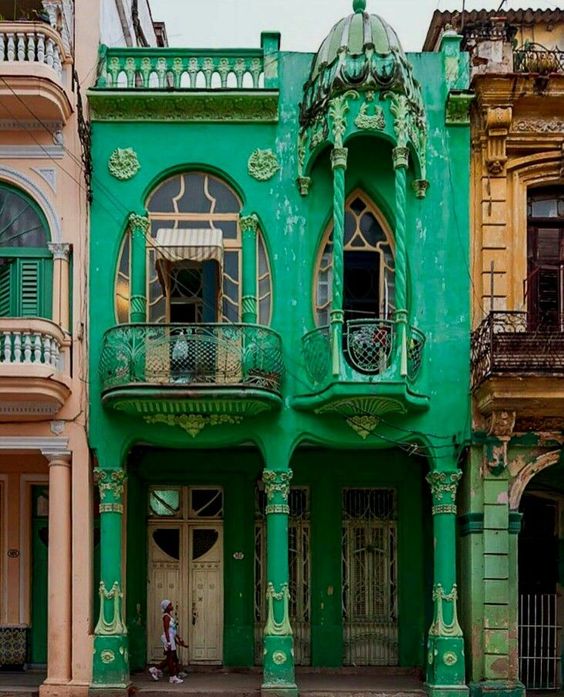 Una casa con caracteristicas del art nouveau por sus curvaturas y columnas con formasrepresentativos del art nouveau, en color verde