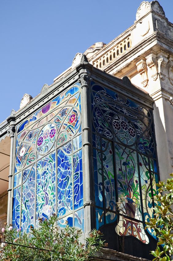 Fotografia de un cuarto al aire libre hecho solamente con vidirales con dibujos de flores y marcos representativos del art nouveau